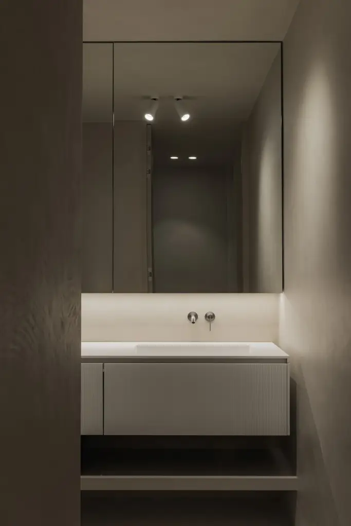Badkamer met wastafel, wandkraan en spiegel met spots, Appartement in Nieuwpoort, interieur Laura Calleeuw