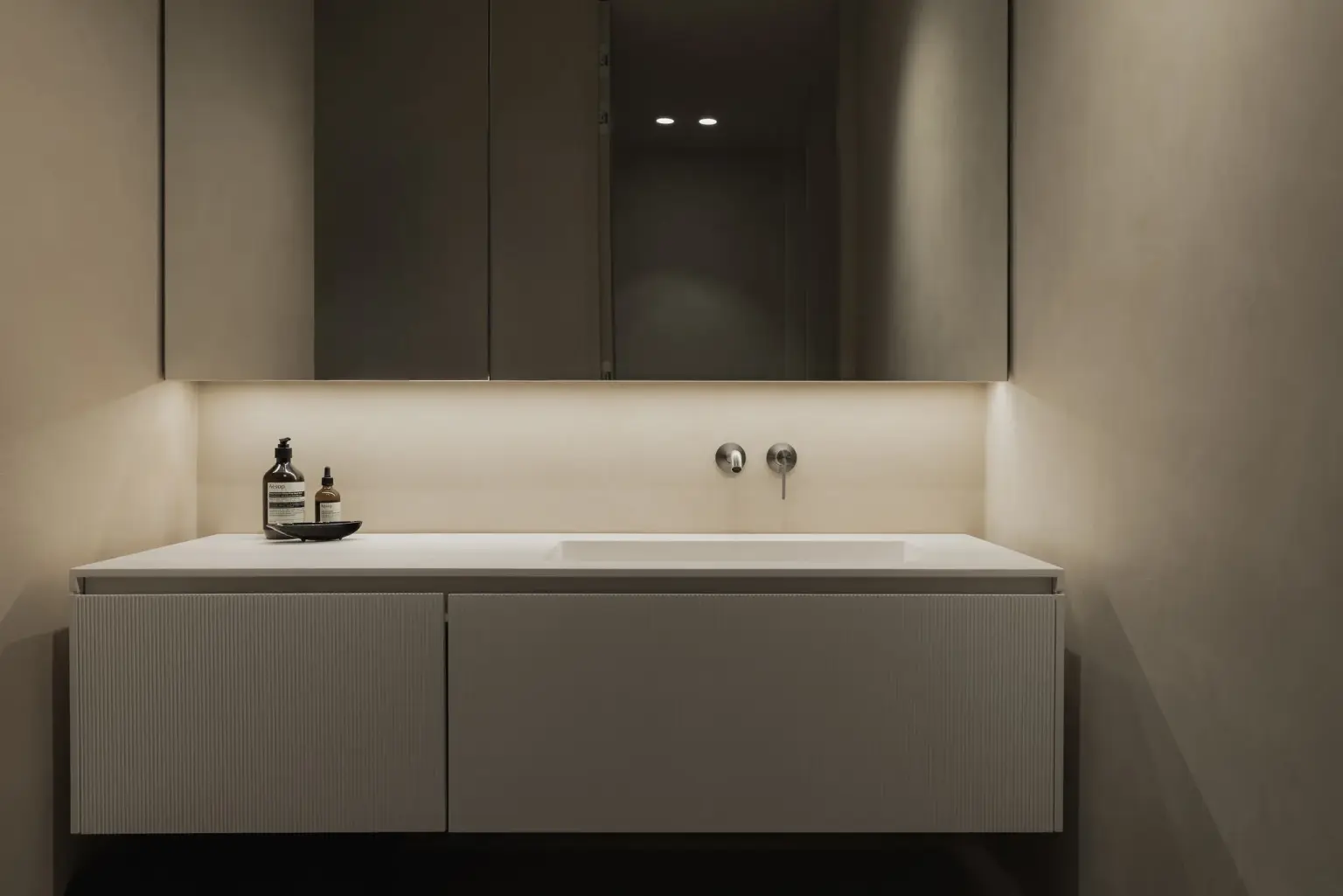 Zwevend wastafelmeubel met wandkraan en indirecte verlichting onder de spiegelkasten, Appartement in Nieuwpoort, interieur Laura Calleeuw