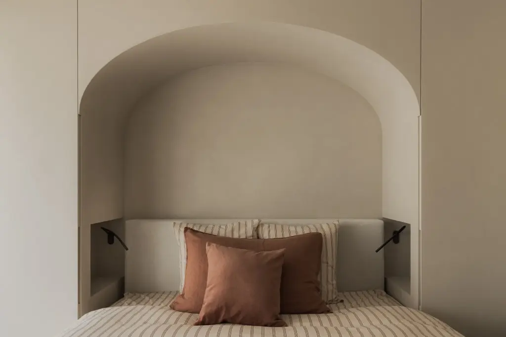 Boogvormige nis met bed tussen witte kastenwanden, Appartement in Nieuwpoort, interieur Laura Calleeuw