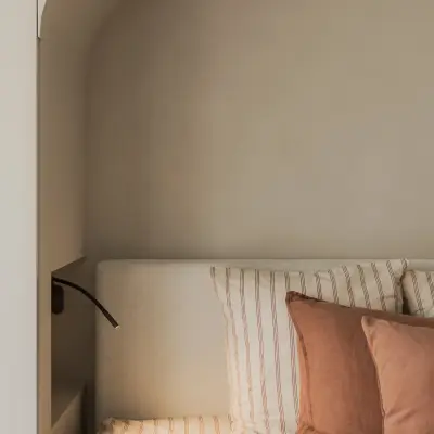 Hoekzicht op het bed in de boogvormige nis met leeslamp, Appartement in Nieuwpoort, interieur Laura Calleeuw