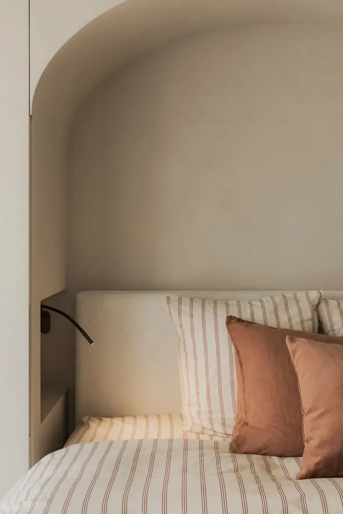 Hoekzicht op het bed in de boogvormige nis met leeslamp, Appartement in Nieuwpoort, interieur Laura Calleeuw