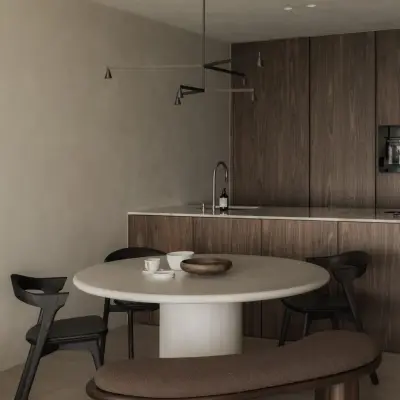 Ronde eettafel met zitbank en zwarte stoelen voor de houten keuken met hanglamp, Appartement in Nieuwpoort, interieur Laura Calleeuw