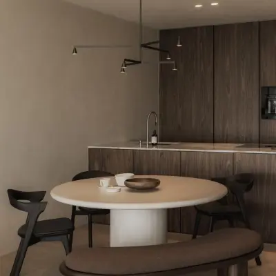 Eethoek met ronde tafel, zwarte stoelen en gebogen zitbank voor een houten keukenwand, Appartement in Nieuwpoort, interieur Laura Calleeuw
