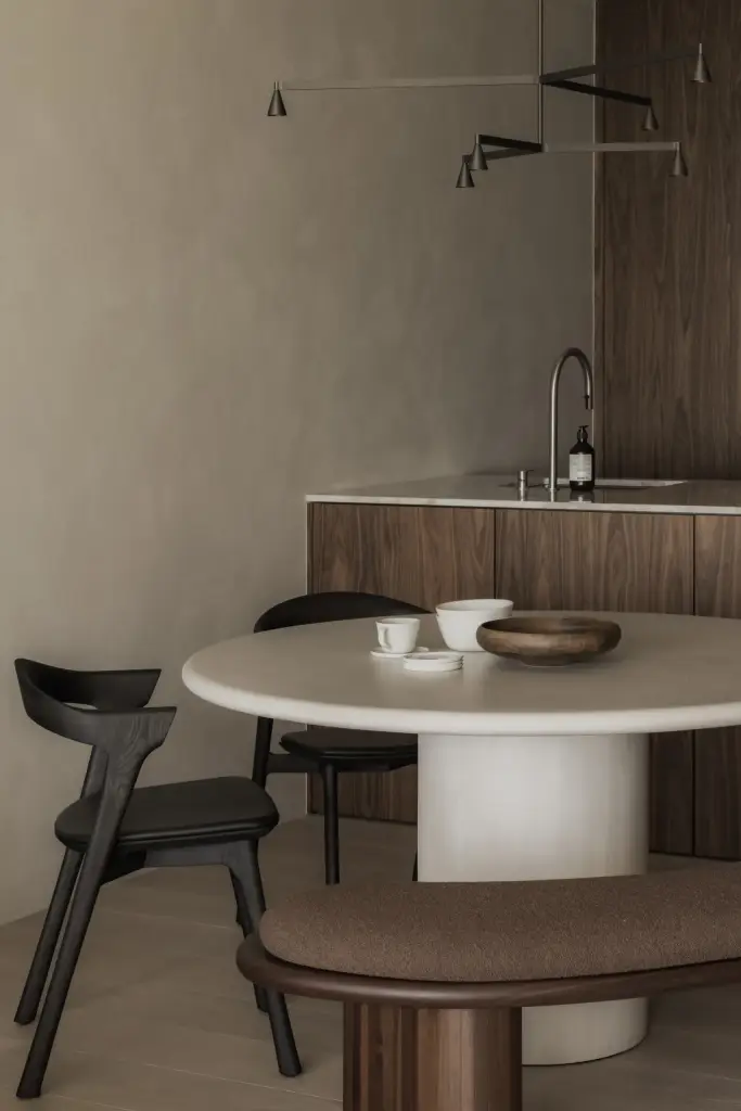 Ronde eettafel met schalen en een zwarte stoel voor de houten keukenwand, Appartement in Nieuwpoort, interieur Laura Calleeuw