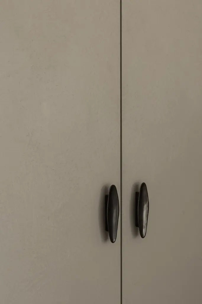 Detail van twee kastdeuren met ronde zwarte handgrepen in gepleisterde afwerking, Appartement in Nieuwpoort, interieur Laura Calleeuw