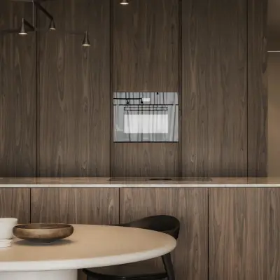 Keuken met houten kastenwand en inbouwoven boven een eettafel met stoelen, Appartement in Nieuwpoort, interieur Laura Calleeuw