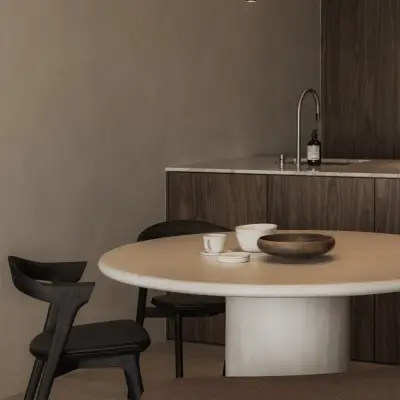 Houten keuken met spoelbak en kraan achter de eettafel met zwarte stoel, Appartement in Nieuwpoort, interieur Laura Calleeuw