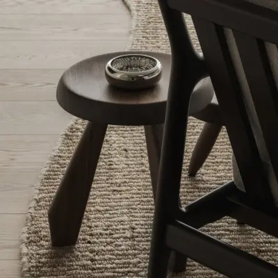 Houten kruk op een jute tapijt naast een houten fauteuil, Appartement in Nieuwpoort, interieur Laura Calleeuw