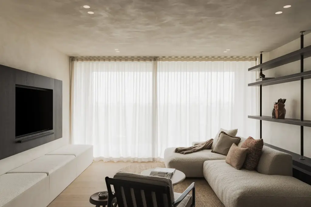 Leefruimte met donkere televisiewand, lage zitbank, sofa en gepleisterd plafond, Appartement in Nieuwpoort, interieur Laura Calleeuw