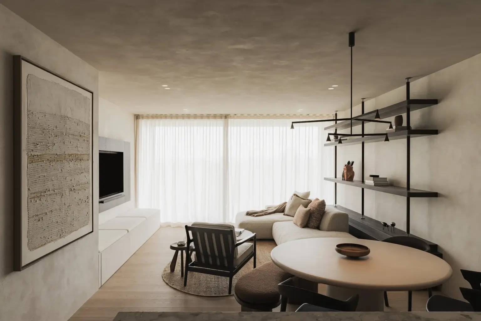 Leefruimte met zithoek, ronde salontafel, open rekken en televisiewand voor grote ramen met vitrage, Appartement in Nieuwpoort, interieur Laura Calleeuw
