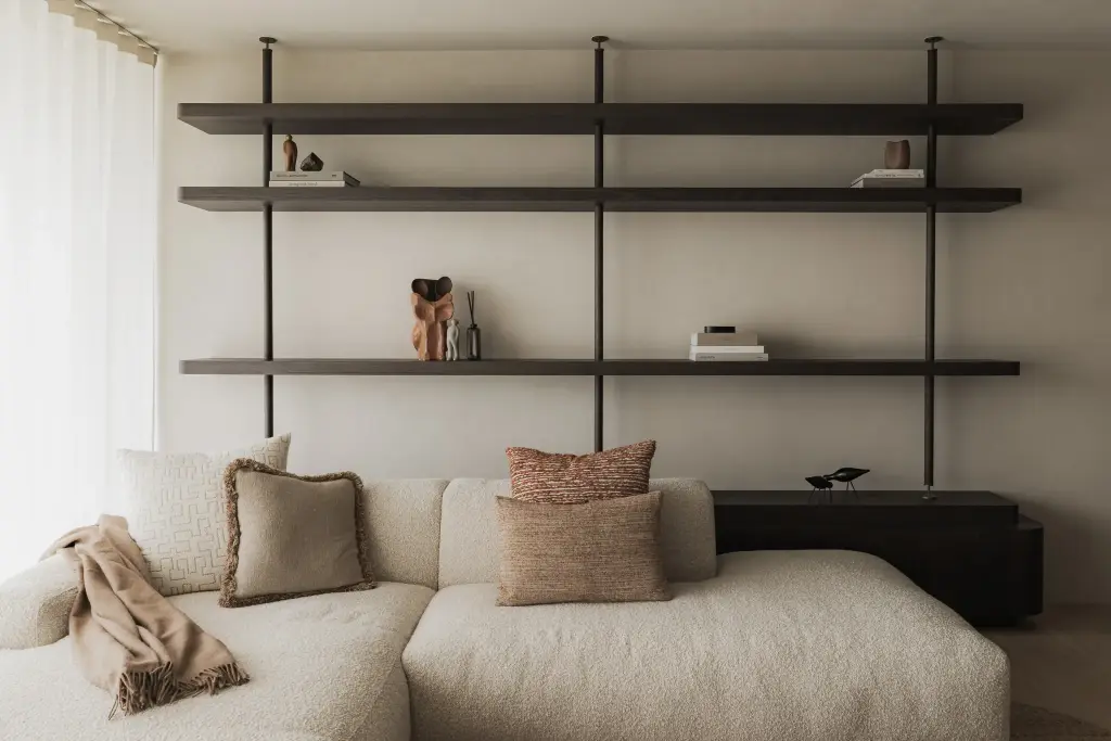 Open rekken in zwart staal en hout boven een sofa met plaid en kussens, Appartement in Nieuwpoort, interieur Laura Calleeuw