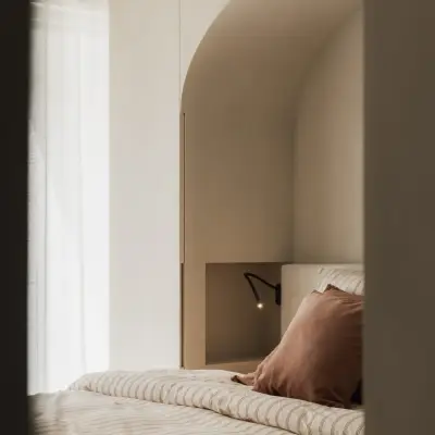 Bed in een boogvormige nis met gordijn en een spiegelende wand, Appartement in Nieuwpoort, interieur Laura Calleeuw