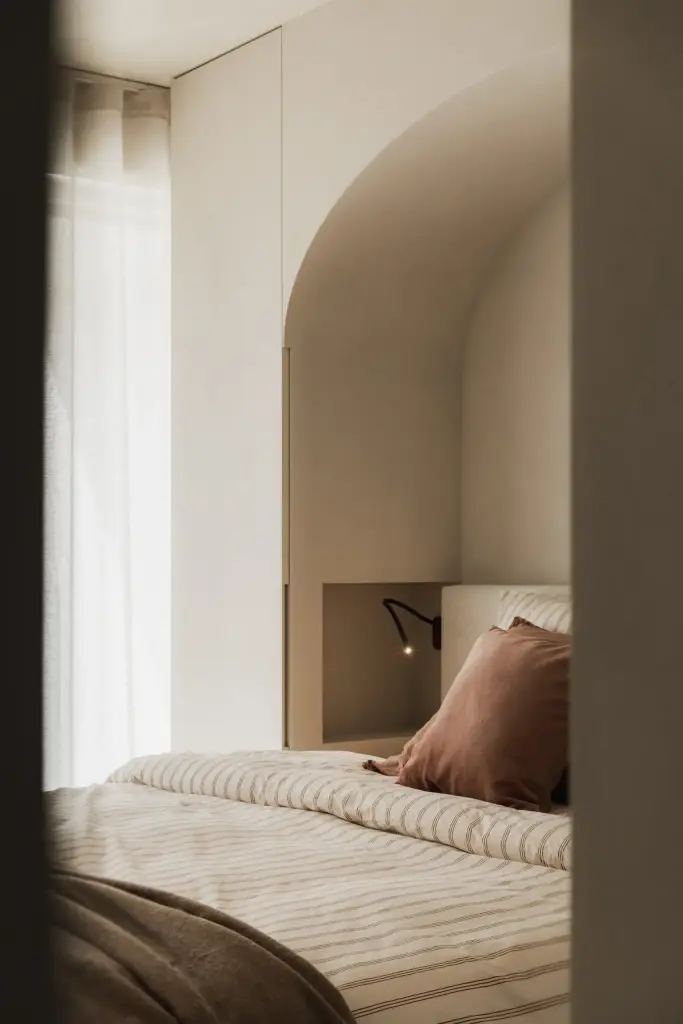 Bed in een boogvormige nis met gordijn en een spiegelende wand, Appartement in Nieuwpoort, interieur Laura Calleeuw