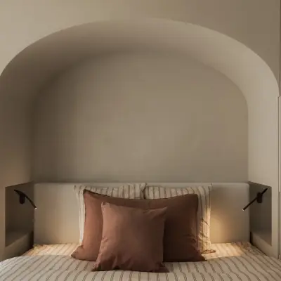 Bed in een boogvormige gepleisterde nis met leeslampjes en terracotta kussens, Appartement in Nieuwpoort, interieur Laura Calleeuw