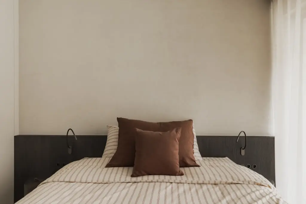 Bed met donker houten hoofdbord, leeslampjes en gordijn, Appartement in Nieuwpoort, interieur Laura Calleeuw