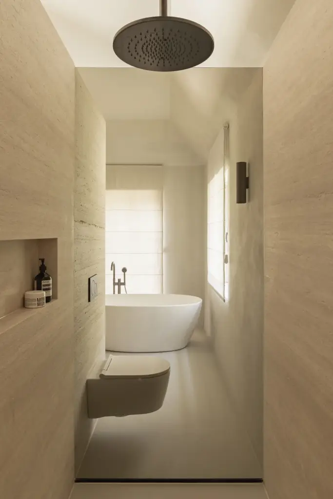 Smalle badkamer met regendouche, hangend toilet en vrijstaand bad voor het raam, Gezinsvilla in Heusden-Zolder, interieur Laura Calleeuw