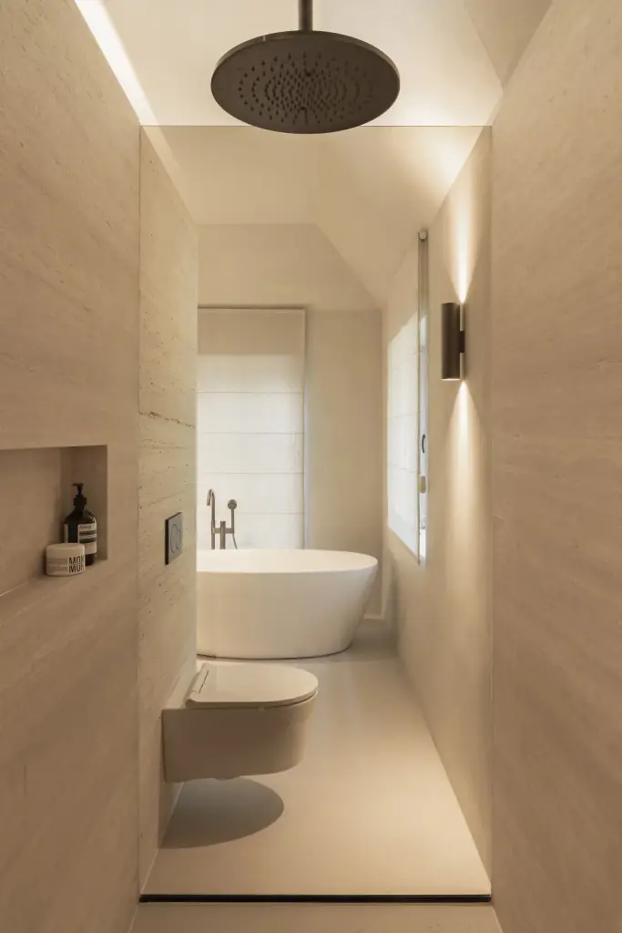 Smalle badkamer met regendouche, hangend toilet en vrijstaand bad voor het raam, Gezinsvilla in Heusden-Zolder, interieur Laura Calleeuw