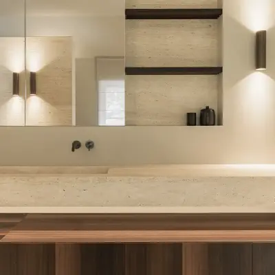 Wastafel in travertijn onder een spiegelkast, met houten onderkast en wandlamp, Gezinsvilla in Heusden-Zolder, interieur Laura Calleeuw