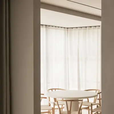 Eethoek met ronde tafel, houten stoelen en hoekraam met vitrage, Gezinsvilla in Heusden-Zolder, interieur Laura Calleeuw