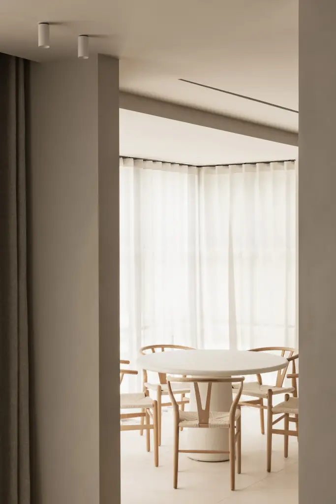 Eethoek met ronde tafel, houten stoelen en hoekraam met vitrage, Gezinsvilla in Heusden-Zolder, interieur Laura Calleeuw