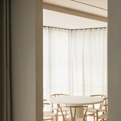 Eethoek met ronde tafel, houten stoelen en hoekraam met vitrage, Gezinsvilla in Heusden-Zolder, interieur Laura Calleeuw