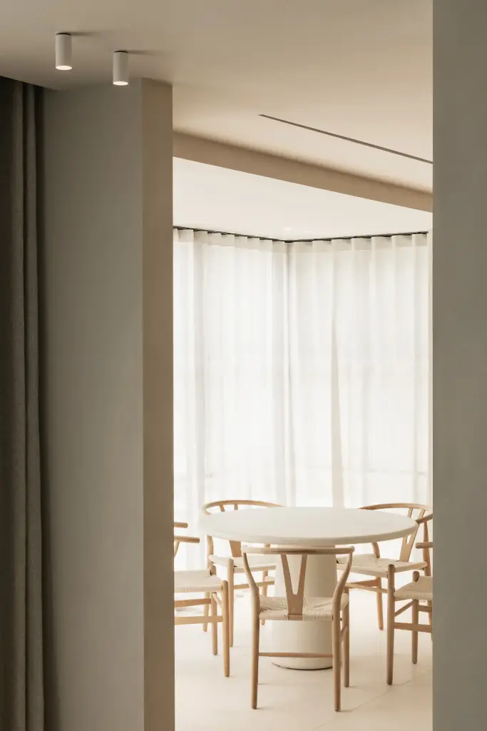 Eethoek met ronde tafel, houten stoelen en hoekraam met vitrage, Gezinsvilla in Heusden-Zolder, interieur Laura Calleeuw