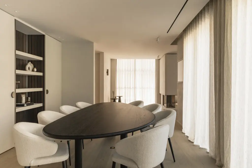 Eetkamer met ovale donkere tafel, ronde stoelen en een verlichte kast met ribbelwand, Gezinsvilla in Heusden-Zolder, interieur Laura Calleeuw