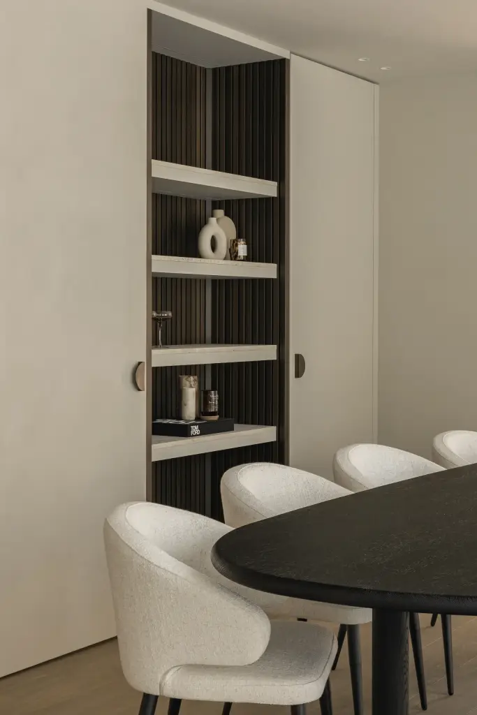 Ovale eettafel met stoelen naast de verlichte kastnis, Gezinsvilla in Heusden-Zolder, interieur Laura Calleeuw