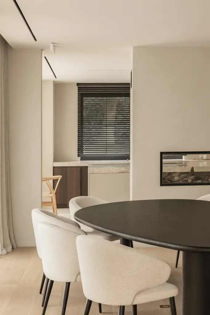 Ovale tafel met ronde witte stoelen en doorkijk naar de haard, Gezinsvilla in Heusden-Zolder, interieur Laura Calleeuw