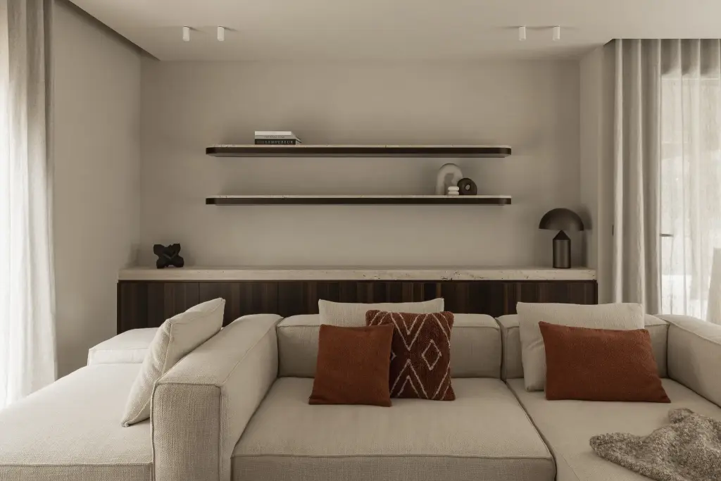 Hoeksofa met terracotta kussens voor een houten kast met verlichte wandplanken, Gezinsvilla in Heusden-Zolder, interieur Laura Calleeuw
