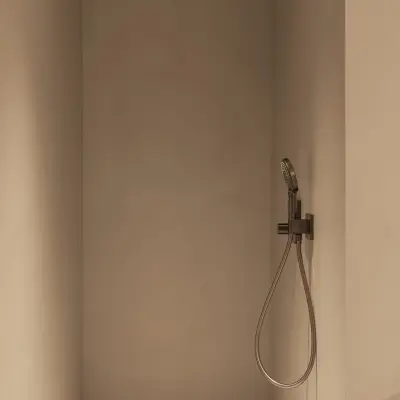 Inloopdouche met zwarte regendouche en handdouche tegen een gepleisterde wand, Gezinsvilla in Heusden-Zolder, interieur Laura Calleeuw