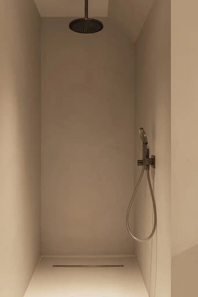 Inloopdouche met zwarte regendouche en handdouche tegen een gepleisterde wand, Gezinsvilla in Heusden-Zolder, interieur Laura Calleeuw