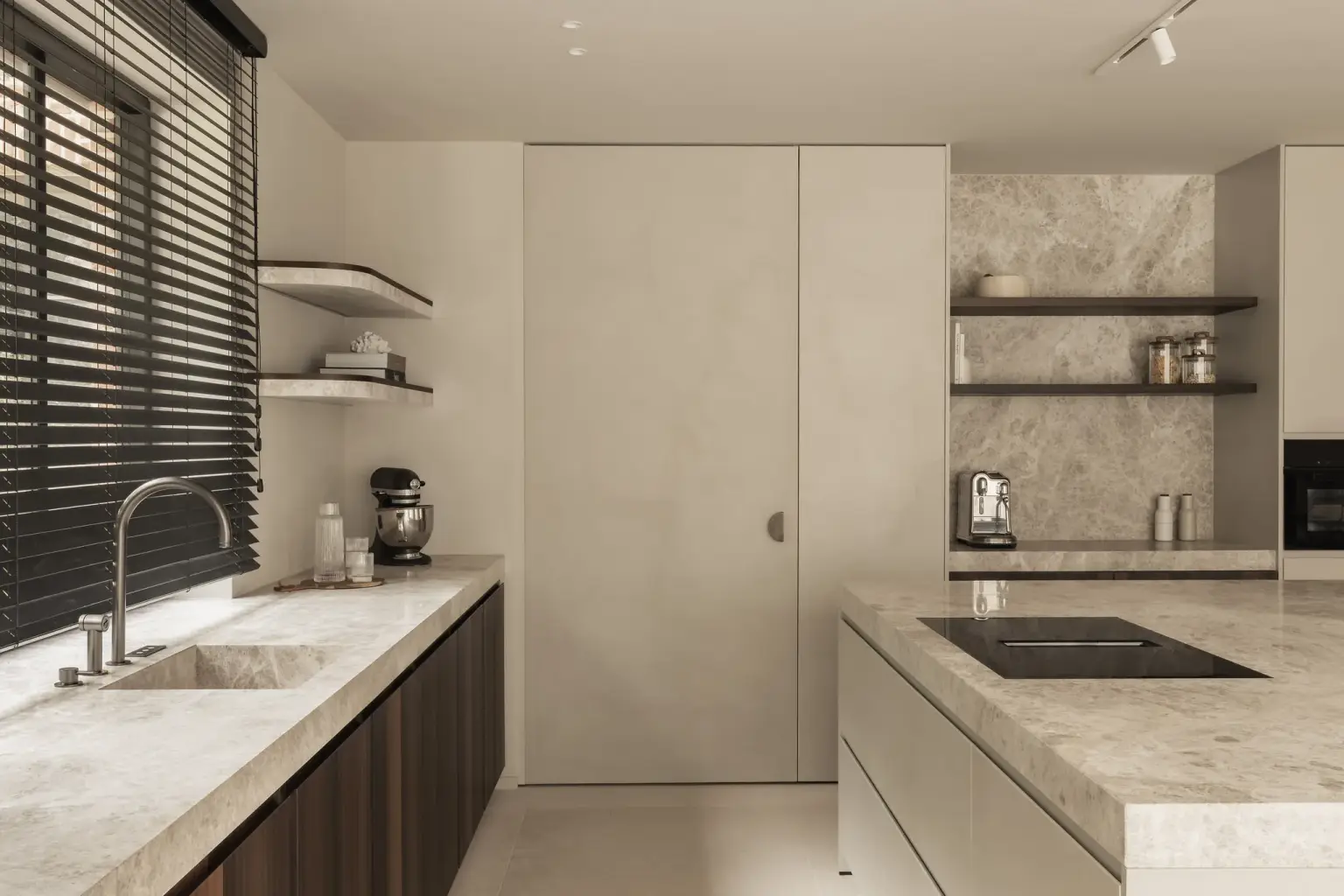 Keuken met natuurstenen kookeiland en spoelbak, houten jaloezieën en een verborgen kastendeur, Gezinsvilla in Heusden-Zolder, interieur Laura Calleeuw