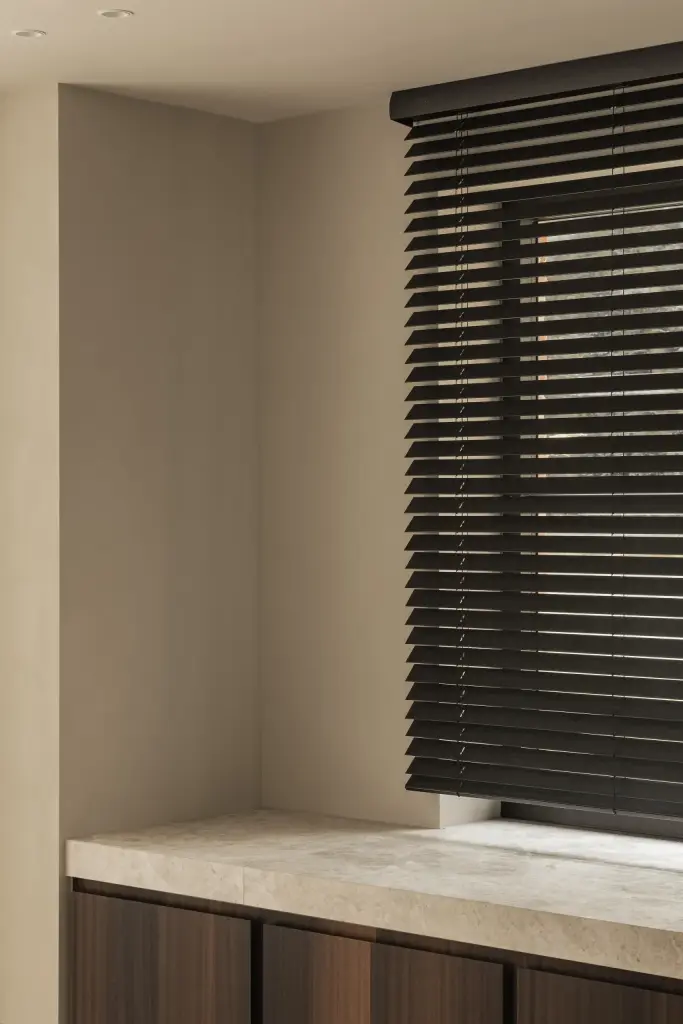 Hoek van de keuken met natuurstenen werkblad voor een raam met jaloezie, Gezinsvilla in Heusden-Zolder, interieur Laura Calleeuw
