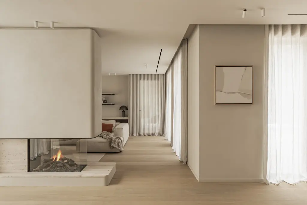 Leefruimte met doorkijk, een open haard in een gepleisterd volume en lange vitrage, Gezinsvilla in Heusden-Zolder, interieur Laura Calleeuw