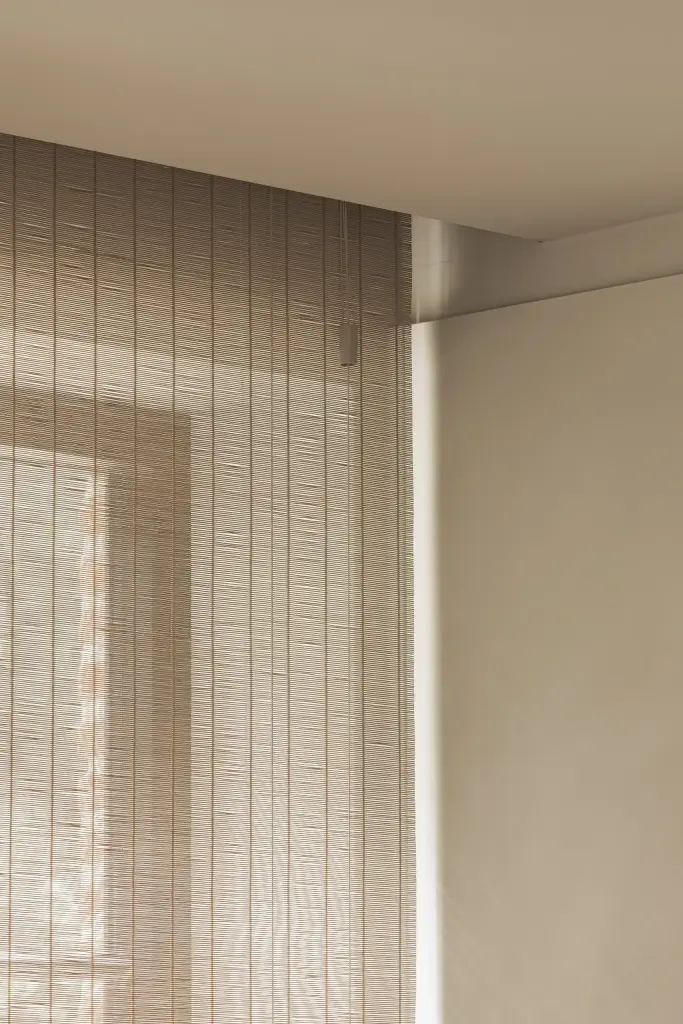 Detail van een rieten raamdecoratie naast een gepleisterde wand, Gezinsvilla in Heusden-Zolder, interieur Laura Calleeuw