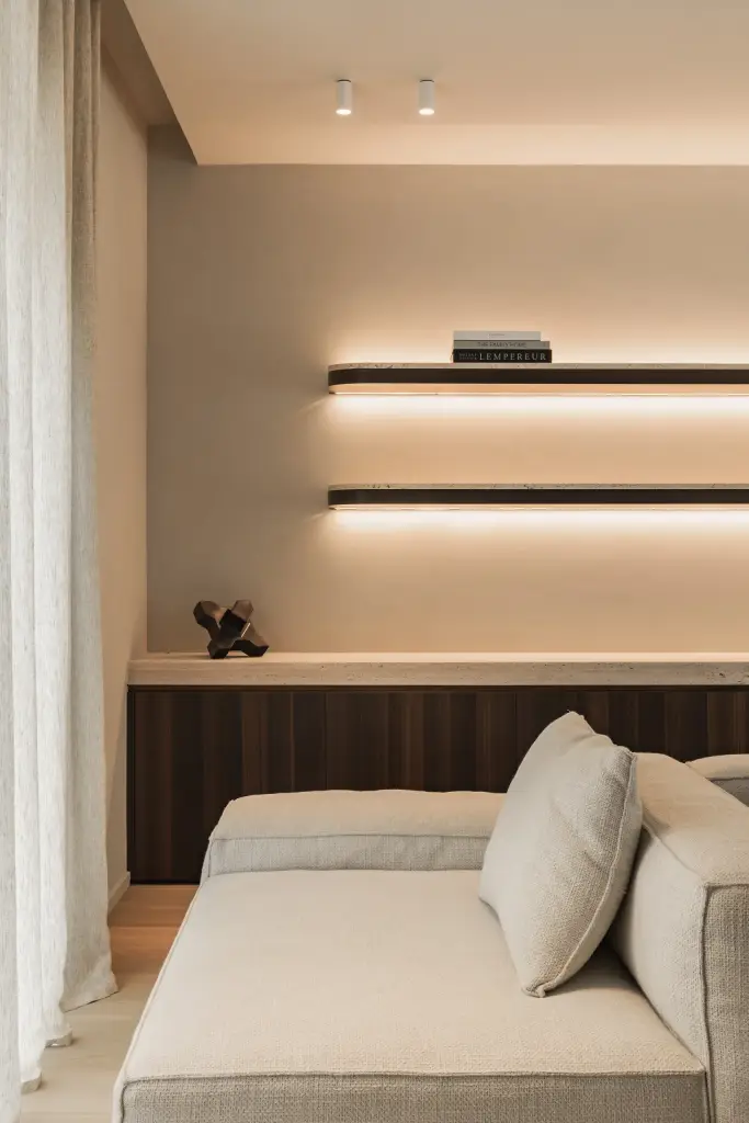 Hoek van de sofa onder wandplanken met indirect licht, Gezinsvilla in Heusden-Zolder, interieur Laura Calleeuw