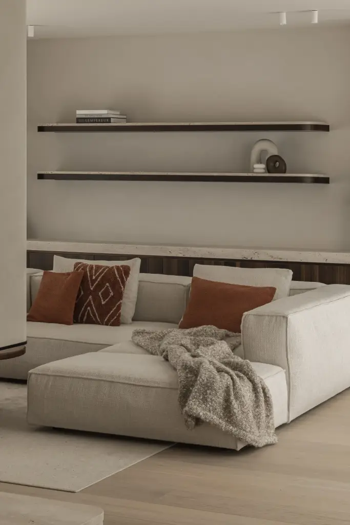 Sofa met plaid en kussens onder planken met een designlamp, Gezinsvilla in Heusden-Zolder, interieur Laura Calleeuw