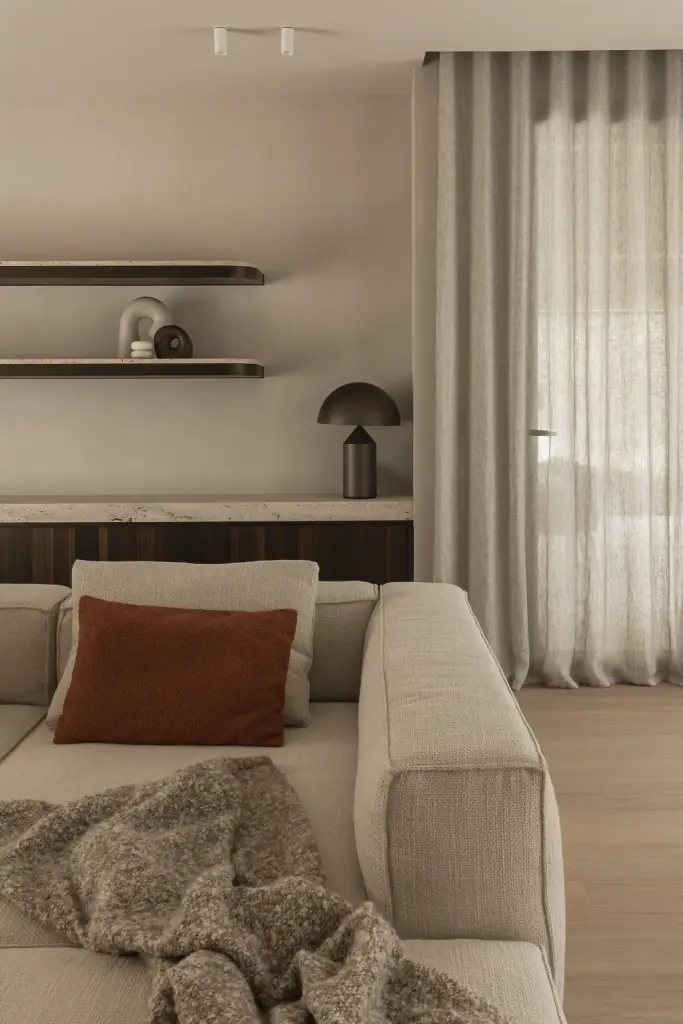Sofa met terracotta kussen naast een gordijn en planken met decoratie, Gezinsvilla in Heusden-Zolder, interieur Laura Calleeuw