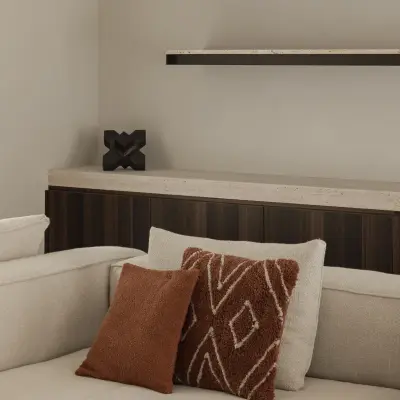 Sofa met terracotta kussens voor een houten kast met verlichte planken, Gezinsvilla in Heusden-Zolder, interieur Laura Calleeuw