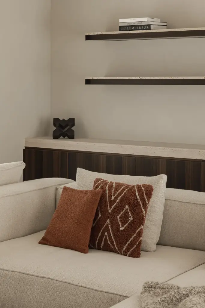 Sofa met terracotta kussens voor een houten kast met verlichte planken, Gezinsvilla in Heusden-Zolder, interieur Laura Calleeuw