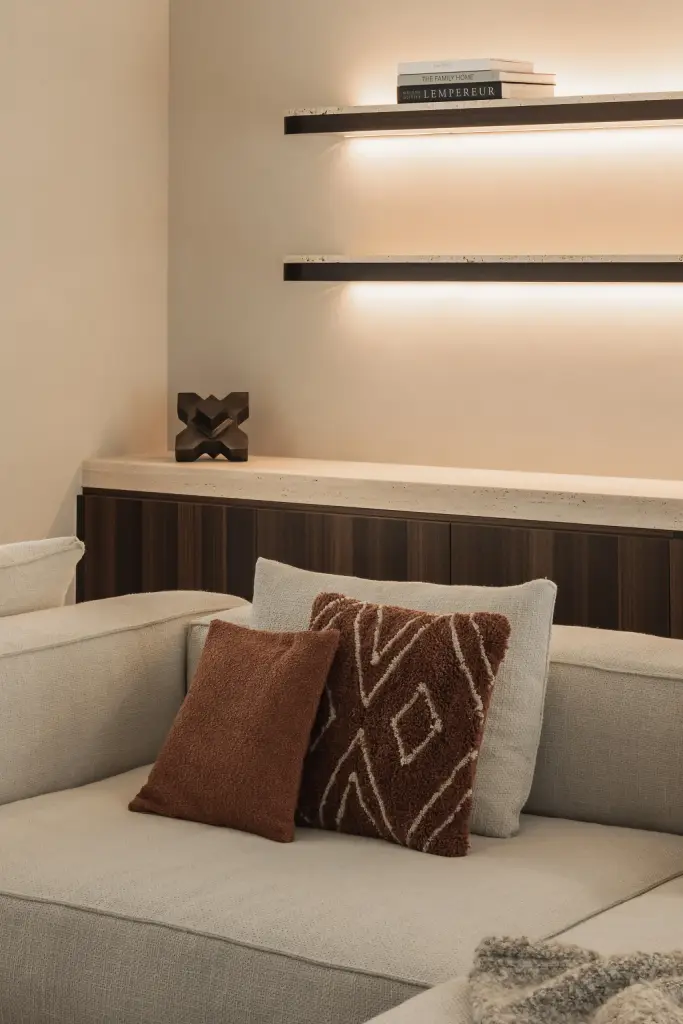 Sofa met terracotta kussens voor een houten kast met verlichte planken, Gezinsvilla in Heusden-Zolder, interieur Laura Calleeuw