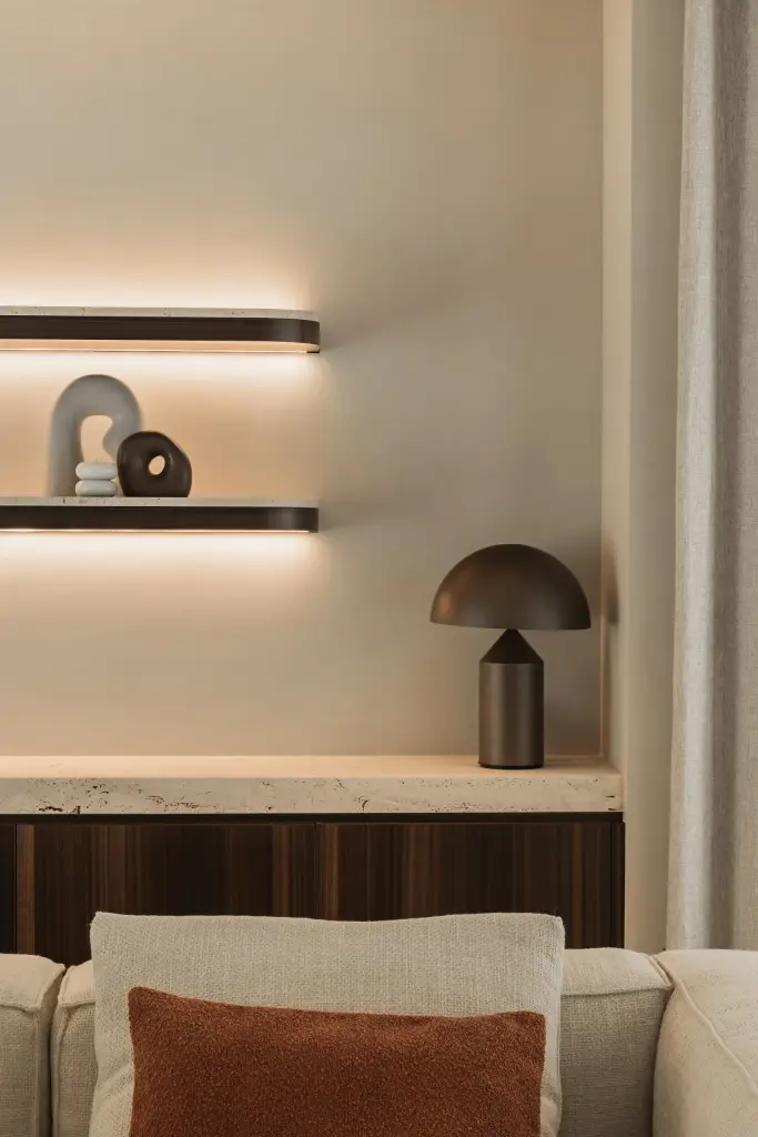 Tafellamp en planken boven een houten kast en sofa met terracotta kussen, Gezinsvilla in Heusden-Zolder, interieur Laura Calleeuw