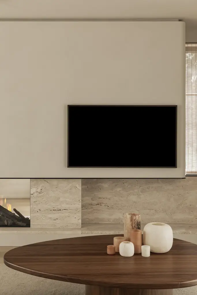 Televisie in een gepleisterd volume boven de natuurstenen haard en salontafel, Gezinsvilla in Heusden-Zolder, interieur Laura Calleeuw