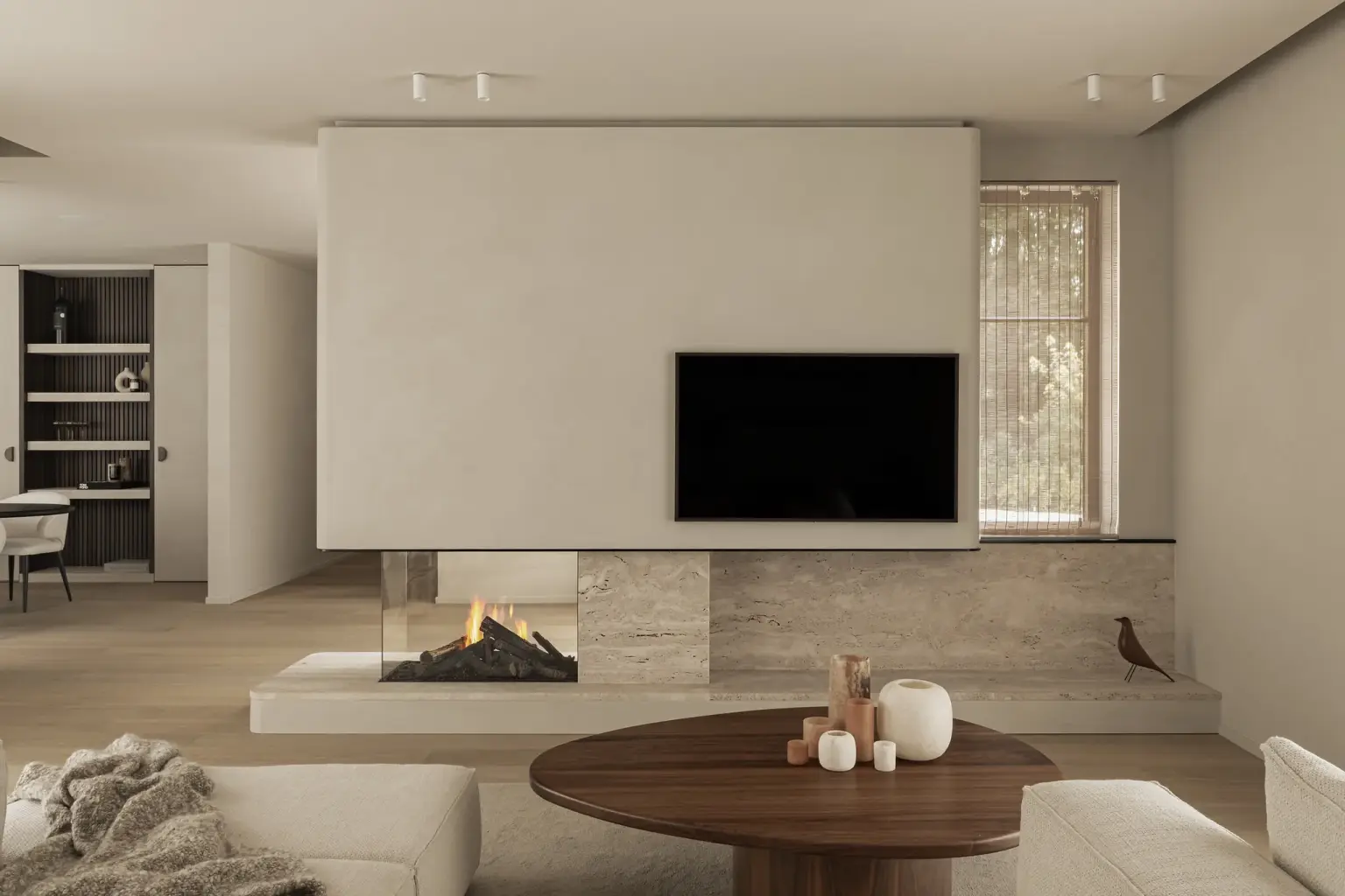 Leefruimte met televisie boven een open haard in natuursteen en een ovale houten salontafel, Gezinsvilla in Heusden-Zolder, interieur Laura Calleeuw