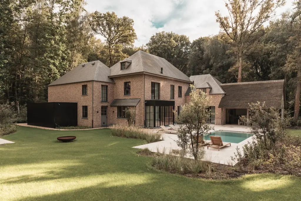 Achterzijde van de baksteenvilla met gazon, zwembad en terras, Gezinsvilla in Heusden-Zolder, interieur Laura Calleeuw
