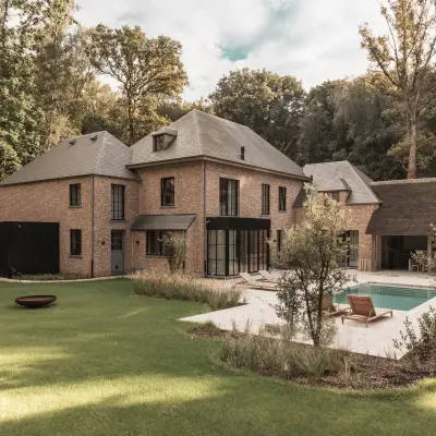 Achterzijde van de baksteenvilla met gazon, zwembad en terras, Gezinsvilla in Heusden-Zolder, interieur Laura Calleeuw