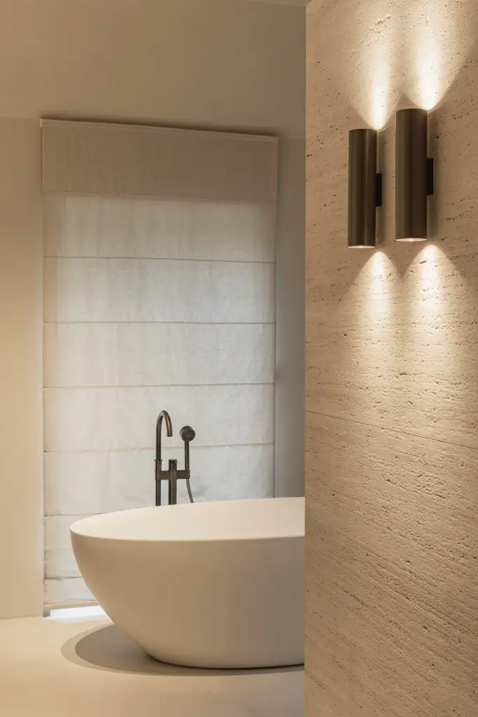 Vrijstaand bad met badkraan, wandlamp en roman blind bij het raam, Gezinsvilla in Heusden-Zolder, interieur Laura Calleeuw