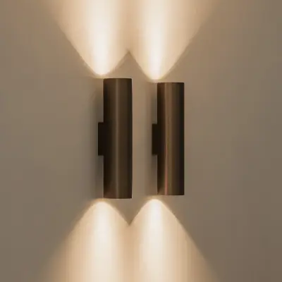 Bronzen wandlamp met licht naar boven en onder tegen een gepleisterde wand, Gezinsvilla in Heusden-Zolder, interieur Laura Calleeuw
