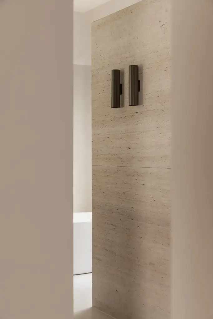 Bronzen wandlamp tegen een travertijnen wand, Gezinsvilla in Heusden-Zolder, interieur Laura Calleeuw